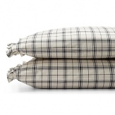 Dramatic black-and-cream checked sheets and pillowcases are edged in feminine pleated ruffles.