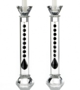 Bask in the good old-fashioned grandeur of Ebony Reflections candlesticks. Luminous columns of clear glass reveal a strand of black chandelier-style beads with luxe faceted detail. Glistening top and bottom detail complete the already-dazzling pair from Lighting by Design.