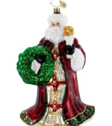 Santa Claus illuminates the holiday with a single candle and his dazzling coat of burgundy, gold and green in this handcrafted ornament by Christopher Radko.