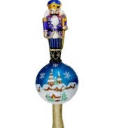 Combining two familiar scenes from the holiday season – a snow-covered village and a classic nutcracker handcrafted in sparkling glass – this elaborate finial puts any tree over the top. By Christopher Radko.