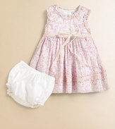 A pretty Liberty Print from England has ruffles and ribbons in this adorable cotton frock.Round ruffled necklineSleevelessEmpire waist with velvet ribbon tiesBack buttonsFull skirt with ruffle and ribbon near hemSolid bloomers with elasticized waist and leg openingsCotton liningCottonDry cleanImported Please note: Number of buttons may vary depending on size ordered. 