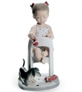 Puppy love. A little girl plays footsie with a furry friend, kicking off her red slippers in a cute Lladro figurine for parents and pet owners.