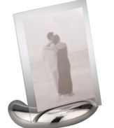 Keep memories fresh in the modern Elbow picture frame. A sculpted metal base turns back in an elegant curve, fitted with sheets of clear glass for displaying any photo, vertical or horizontal. Designed by Neil Cohen for Nambe.