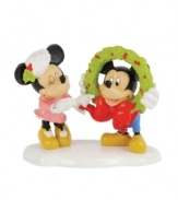 Mickey and Minnie flirt with a little Christmas romance, giggling as they put the finishing touches on a Mickey's Village holiday wreath. By Department 56.