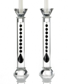 Bask in the good old-fashioned grandeur of Ebony Reflections candlesticks. Luminous columns of clear glass reveal a strand of black chandelier-style beads with luxe faceted detail. Glistening top and bottom detail complete the already-dazzling pair from Lighting by Design. Bask in the good old-fashioned grandeur of Ebony Reflections candlesticks. Luminous columns of clear glass reveal a strand of black chandelier-style beads with luxe faceted detail. Glistening top and bottom detail complete the already-dazzling pair from Lighting by Design.